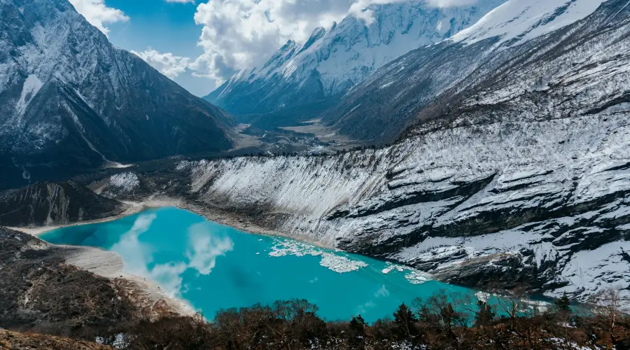 A snowy mountain lake, Birendra Taal, with a serene landscape of snow-covered ground and towering peaks.