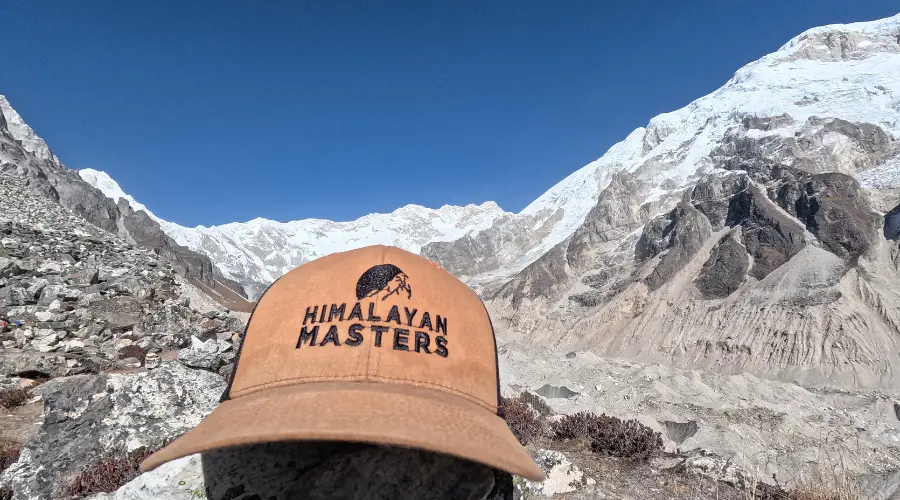 Himalayan Masters branded cap with stunning mountain views in the background