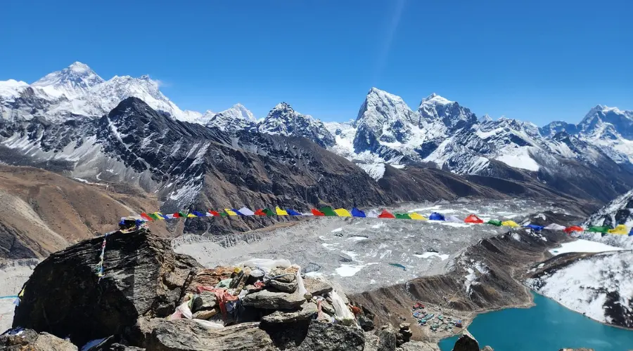 Jaw-dropping Himalayas, along with prayer flags fluttering, and a small, remote village and lake at the bottom
